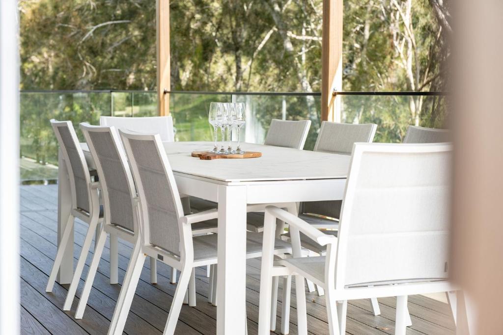 a white dining room table and chairs on a deck at Bangalow in Elizabeth Beach