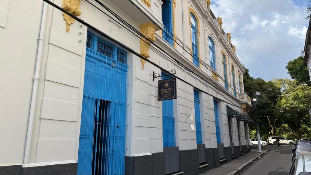 un bâtiment avec des portes bleues et blanches dans une rue dans l'établissement General Hostel Belém, à Belém