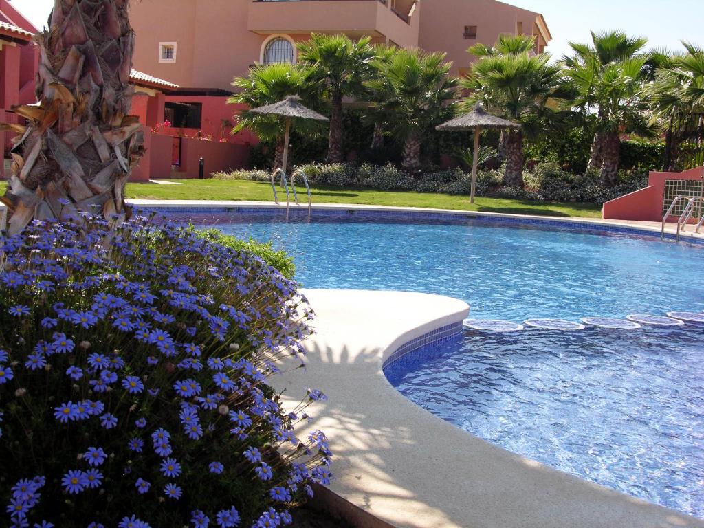 ein Pool mit blauen Blumen vor einem Haus in der Unterkunft Arona 1 - 3208 in Mar de Cristal