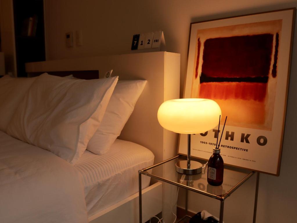 a bedroom with a bed and a table with a lamp at Cozy Seomyeon House in Busan