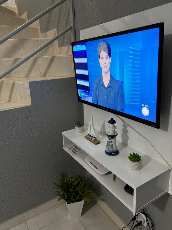 a flat screen tv sitting on a white shelf at Sobrado confortável a uma quadra do mar. in Matinhos