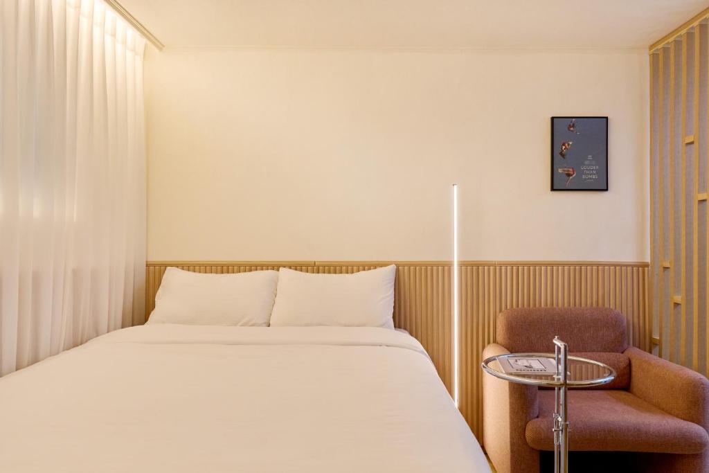 a bedroom with a bed and a chair at Bom Noon Stay Jamsil 봄눈스테이 잠실 in Seoul