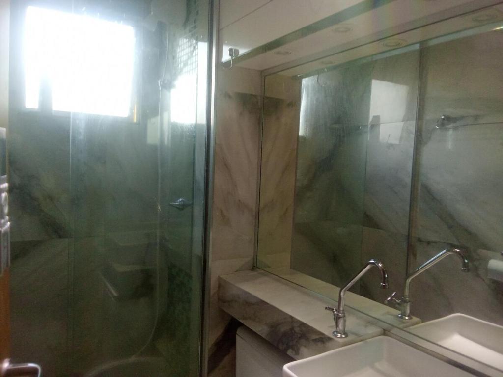 a bathroom with a sink and a glass shower at 1108 Apartamento refrigerado completo para 8 pessoas in Várzea Grande