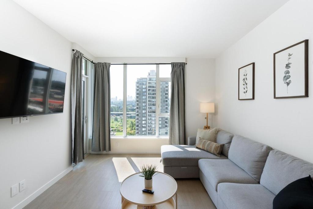 バーナビーにあるModern 1BR Condo, Sleeps 4 with Views, AC, Balcony, Near SkyTrainのソファとテーブルのあるリビングルーム