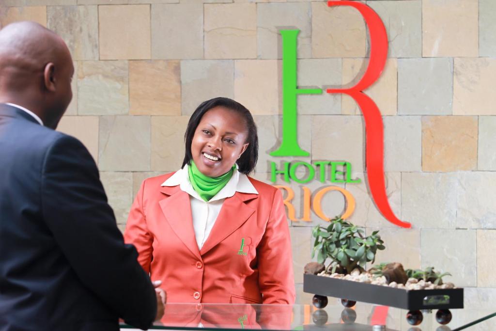 a woman in a red suit talking to a man at Hotel Rio in Nairobi