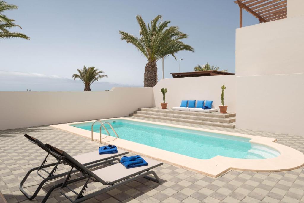 a villa with a swimming pool and two chairs at Villas Salinas in Costa Teguise