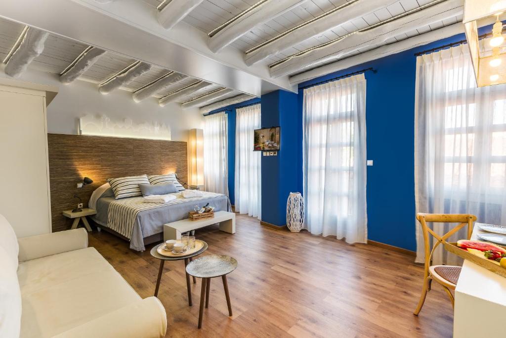 sypialnia z niebieskimi ścianami, łóżkiem i kanapą w obiekcie Sette Venti Boutique Hotel w Chanii