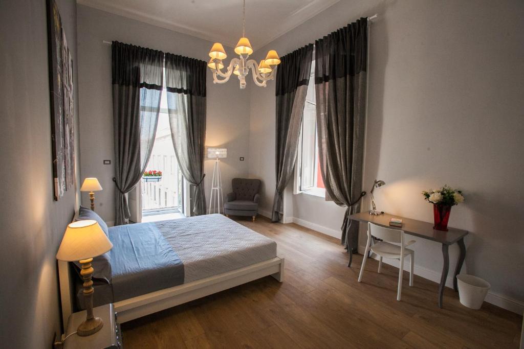 a bedroom with a bed and a desk and windows at Largo Donnaregina Home in Naples