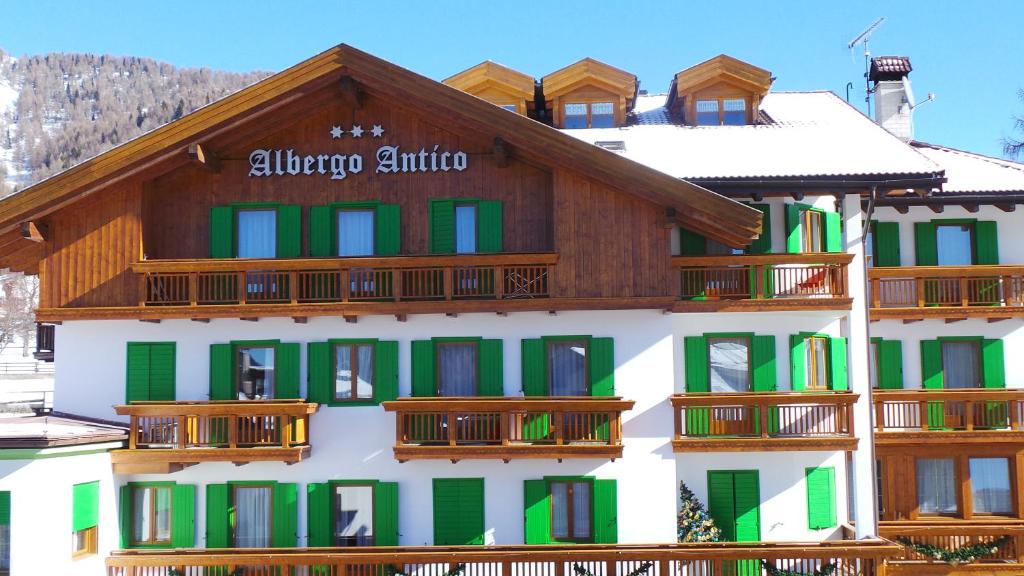 un edificio con ventanas verdes y blancas y balcones de madera en Albergo Antico, en Predazzo