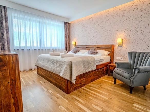 a bedroom with a large bed and a chair at Vysoké Tatry - ISC RESORT in Mlynica