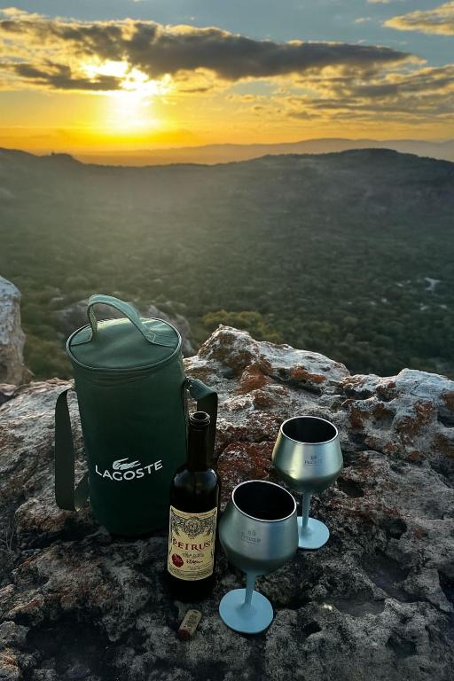a bottle of wine and two servers on top of a mountain at Ecocamping Okaeté in Buíque