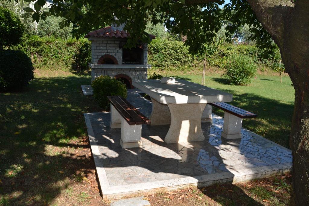 a picnic table and two benches in a park at Apartment Poesia in Poreč