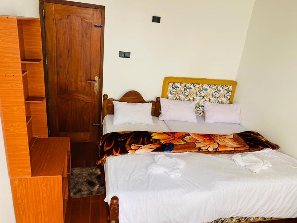 a bedroom with two beds and a wooden door at Avocado City Guest Nuwaraeliya in Nuwara Eliya