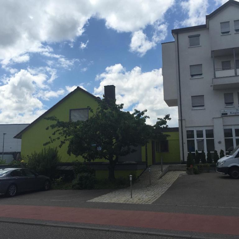 un edificio amarillo y verde junto a un edificio blanco en Gasthaus Keglerklause, en Schwieberdingen
