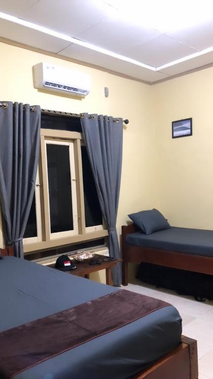 a bedroom with a bed and a window with curtains at Jenny's Bamboo Surf Camp in Karbang