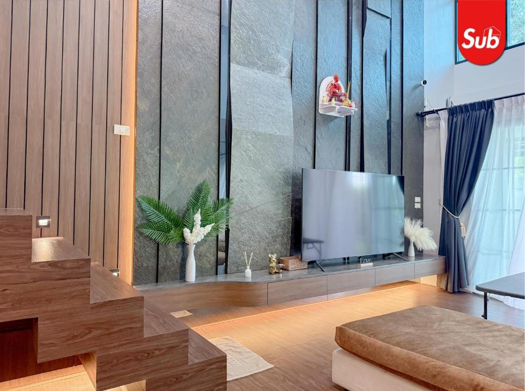a living room with a flat screen tv on a wall at Family Pool Villa, BBQ with Warm Welcome in Ban Nok