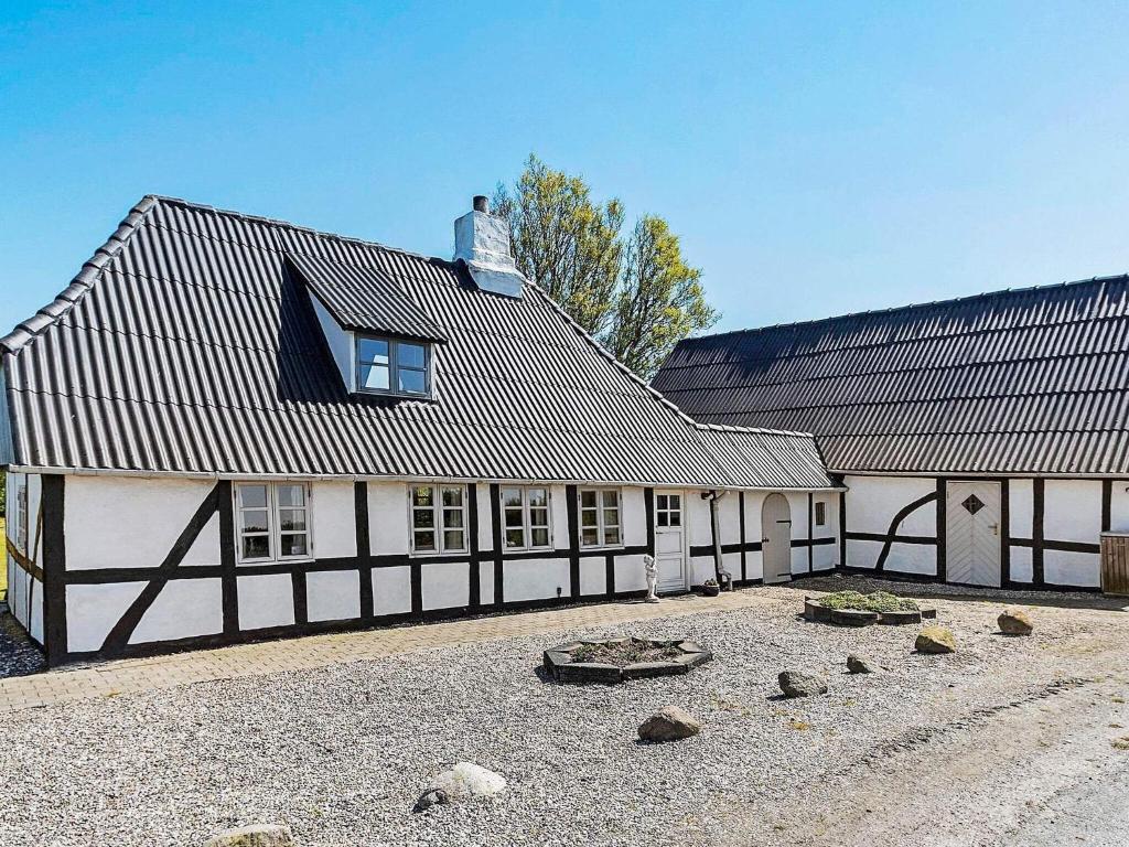 a white and black building with rocks in front of it at 4 person holiday home in Tranekær in Tranekær