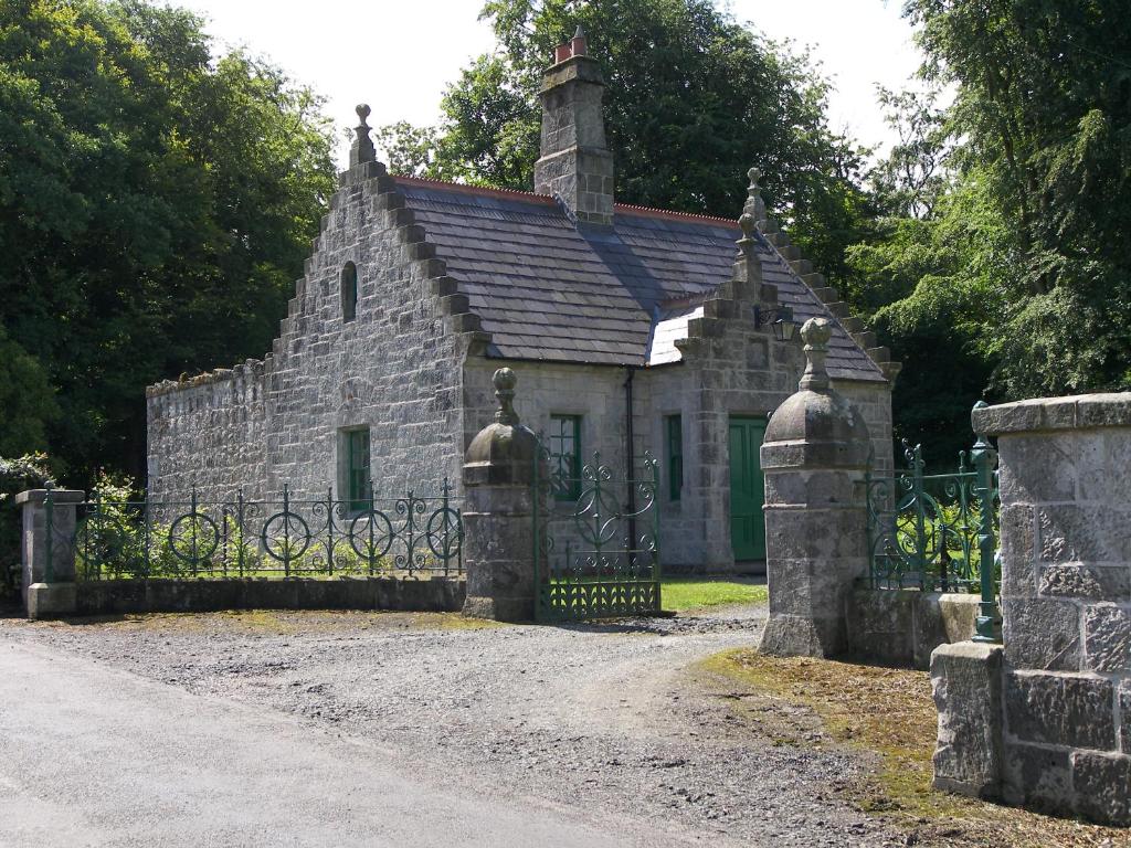 ein altes Steinhaus mit einem Tor davor in der Unterkunft Magherintemple Lodge in Ballycastle