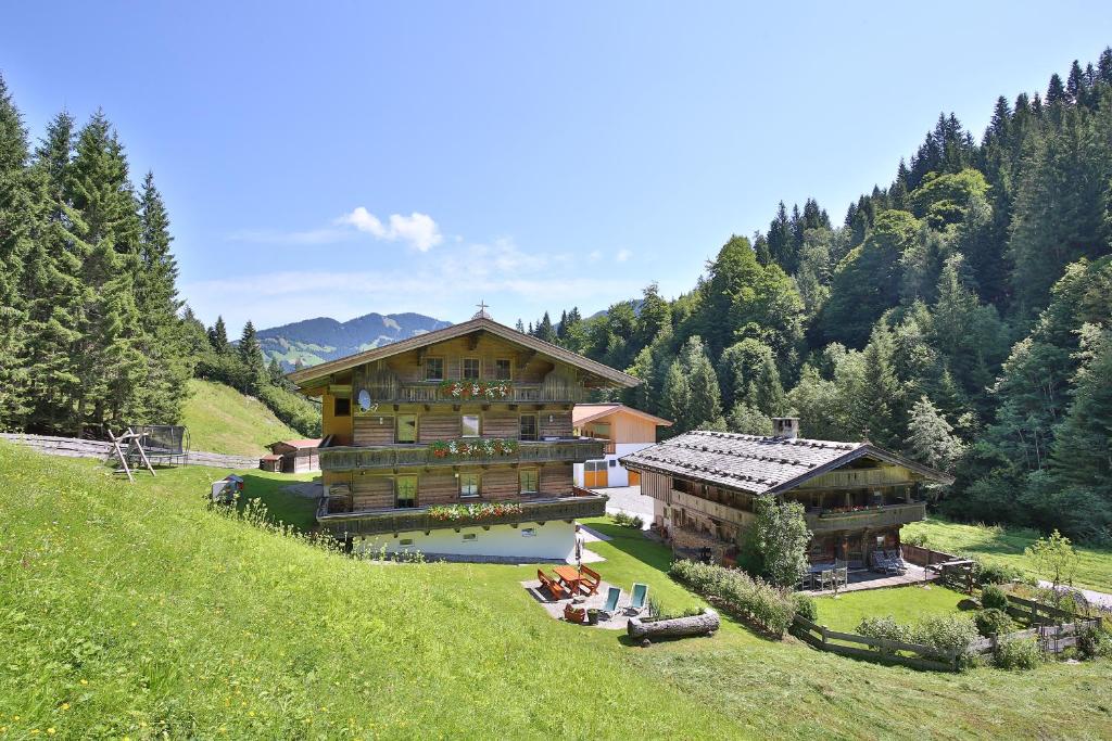 a large wooden building on a hill with trees at Alpboden in Auffach