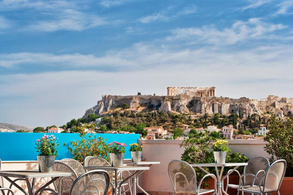 アテネにあるアリオン アテネ ホテルのテーブルと椅子付きのレストランからアクロポリスの景色を望めます。