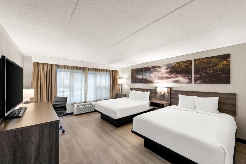 a hotel room with two beds and a flat screen tv at Clarion Pointe Rhinelander Downtown in Rhinelander