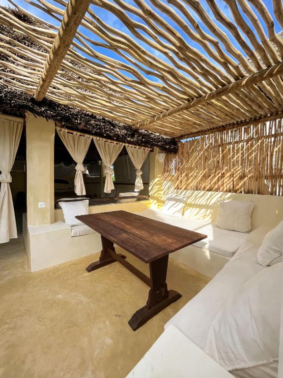 a room with a wooden table and some beds at La Joya Lamu in Shela