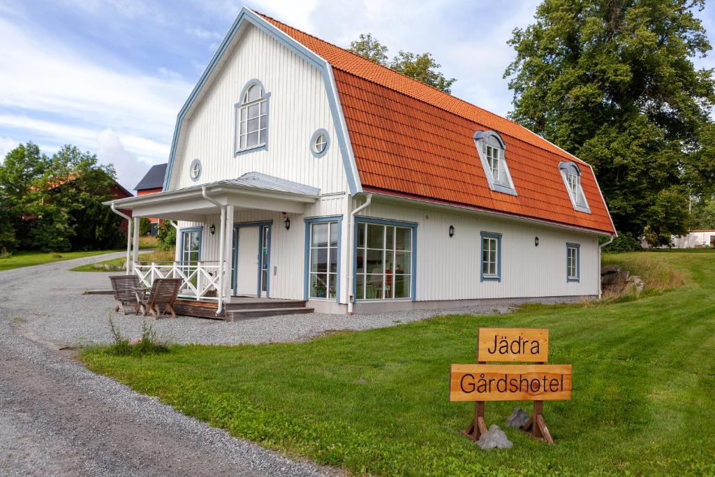 una casa blanca con techo naranja y una señal en Jädra Gårdshotel, en Enköping