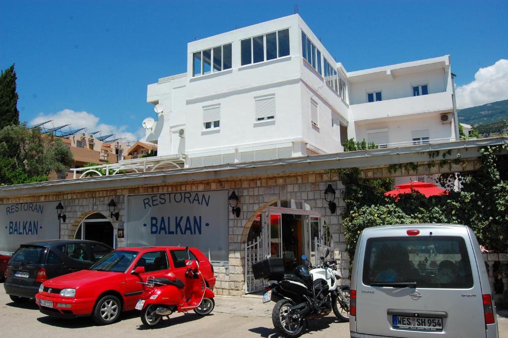 a building with cars and motorcycles parked in a parking lot at Mediterranean Guest House Balkan in Budva