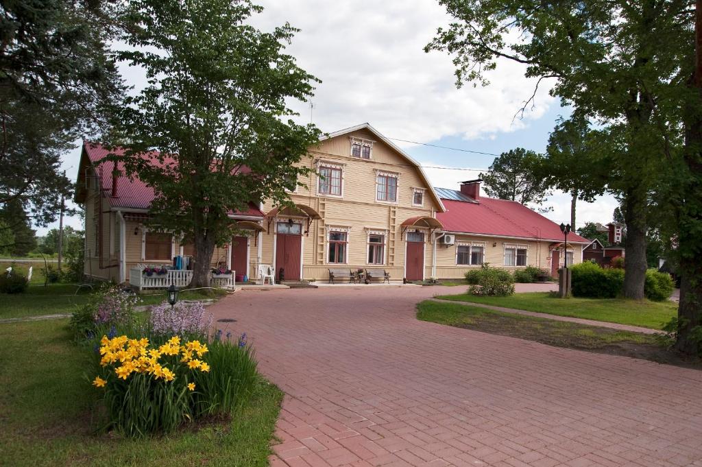 une grande maison avec une allée en briques et des fleurs dans l'établissement Kartano Hostel, à Kokemäki