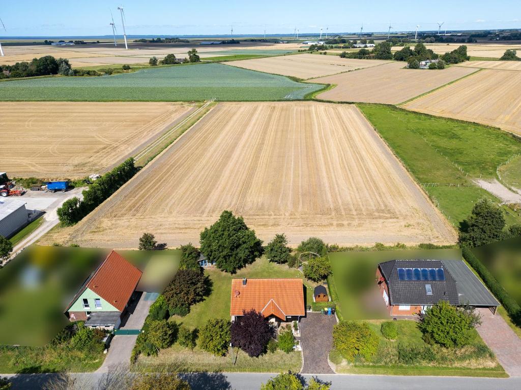 eine Luftansicht eines Betriebs mit einem Feld in der Unterkunft Hus Föfftein in Hellschen-Heringsand-Unterschaar