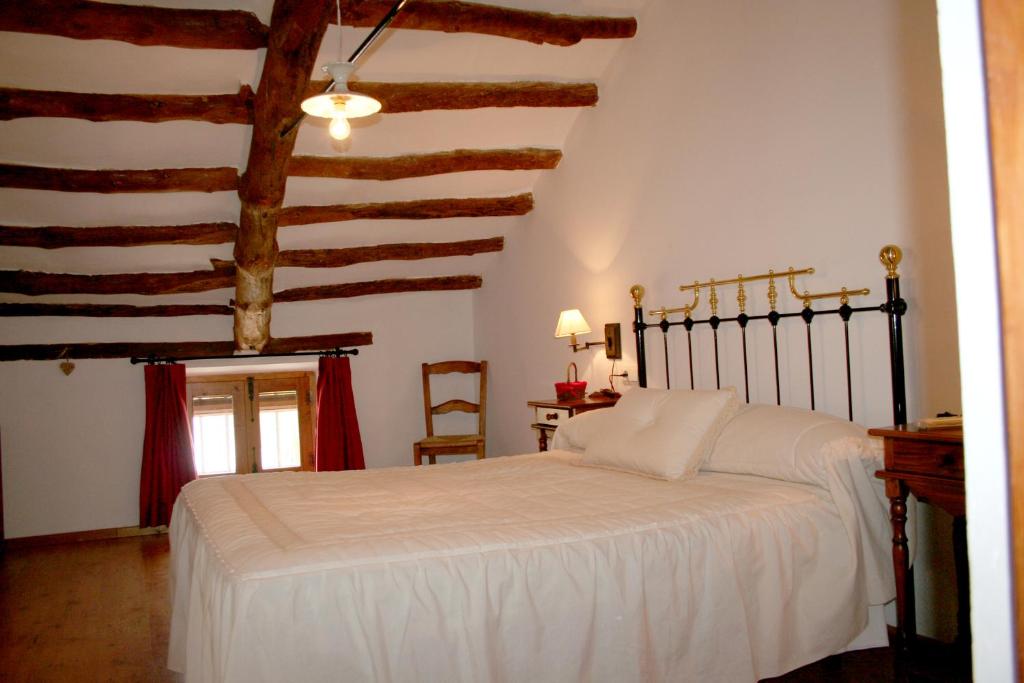 a bedroom with a white bed and wooden ceilings at La Casona de Mahora in Mahora