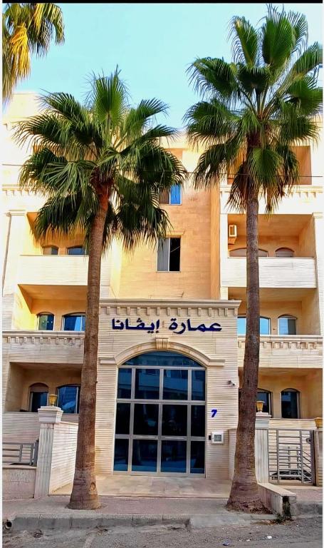 two palm trees in front of a building at EVANNA SUITE & HOTELs VIP ايفانا للشقق الفندقيه VIP in Amman