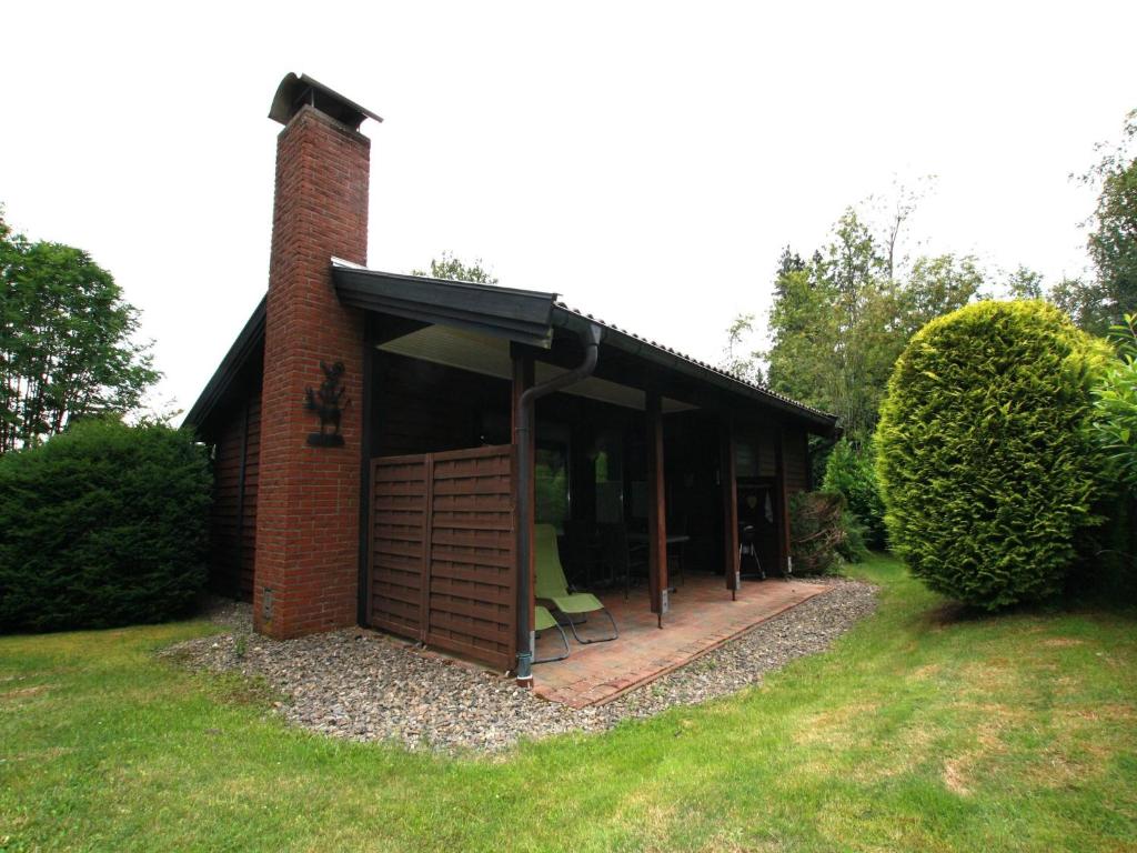 a brick house with a porch with a green chair at Ferienhaus in der Nähe des Sees, Haustierfrei in Clausthal-Zellerfeld