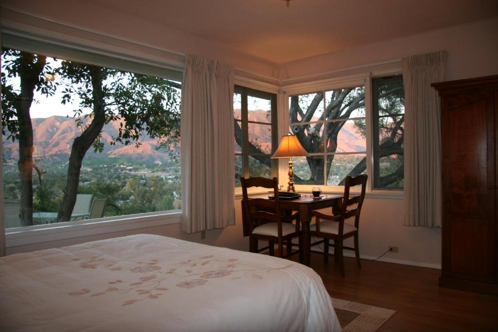 una camera da letto con tavolo, sedie e una grande finestra di Ojai Retreat & Inn a Ojai