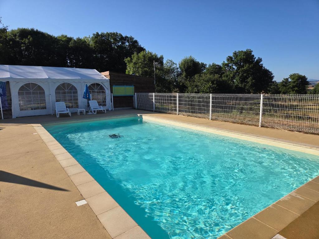 a swimming pool with a tent in the background at Camping des Papillons in Lalizolle