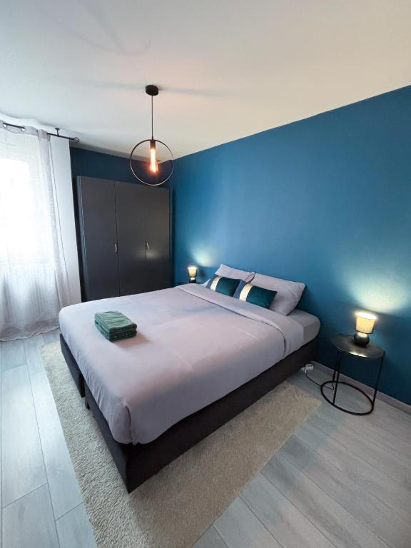 een slaapkamer met een groot bed met een blauwe muur bij Lescapade à Colmar in Colmar