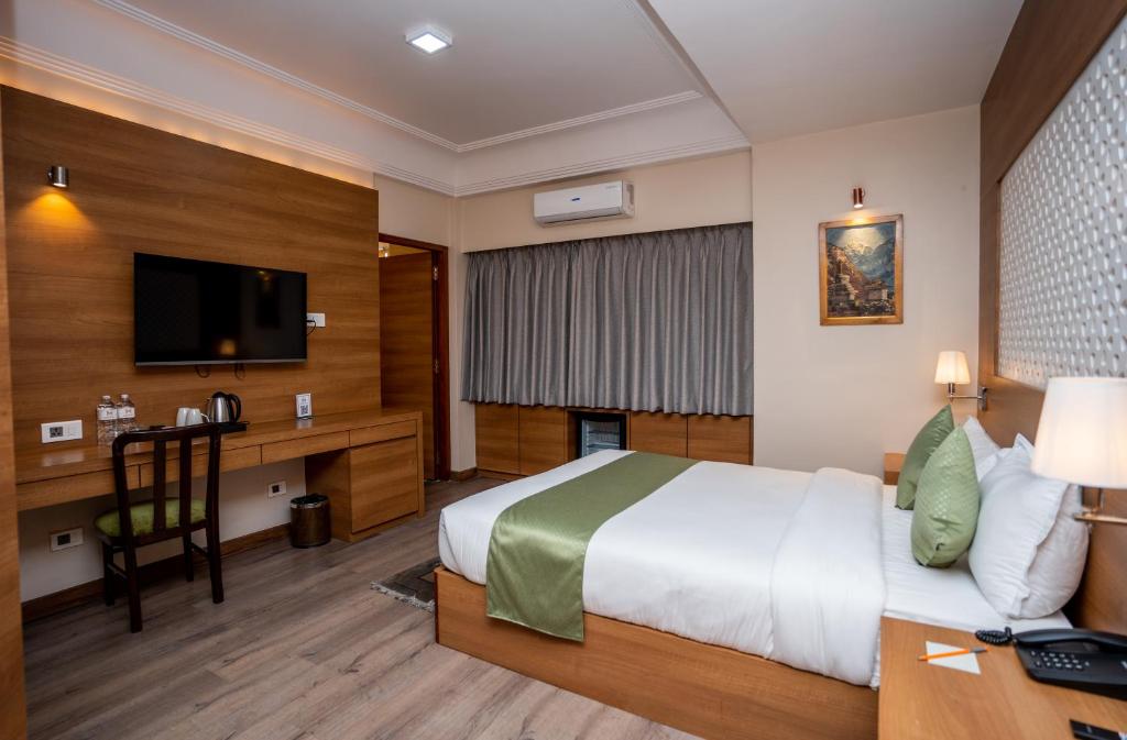 a hotel room with a bed and a desk and a television at Hotel Marcopolo in Kathmandu