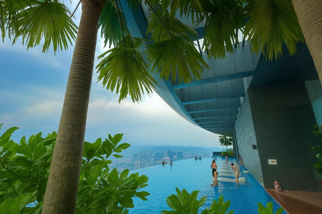 a view of the infinity pool at the top of a building with palm trees at Eaton Suites KL By Luna in Kuala Lumpur