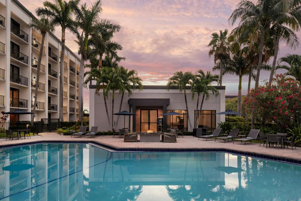 a pool at a hotel with palm trees at Courtyard Fort Lauderdale East Lauderdale-by-the-Sea in Fort Lauderdale