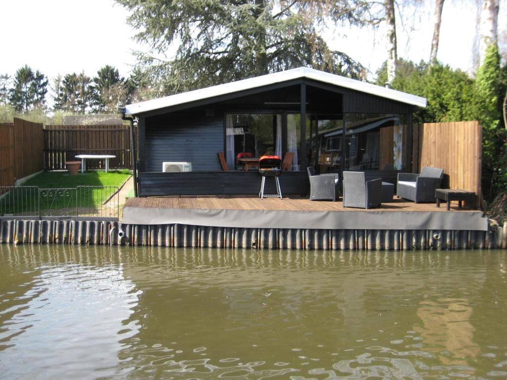 a tiny house on a dock next to a body of water at Modern waterfront chalet in Geel