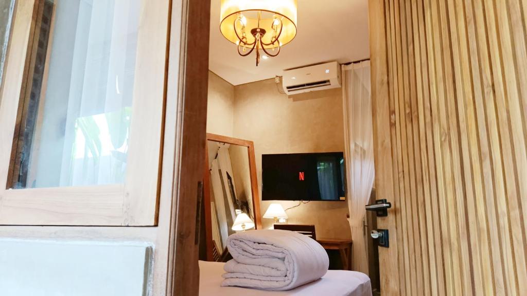 Habitación con cama, ventana y lámpara de araña. en Victory Beloved House Sanur Private Rooms Villa Bali, en Sanur