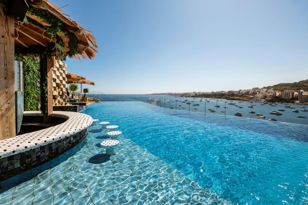 a swimming pool next to a body of water at Damare Resort & SPA in St. Paul's Bay