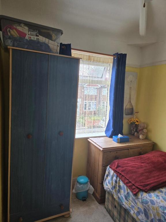 een slaapkamer met een blauwe kast en een raam bij Single Sunny Stretford Room in Manchester