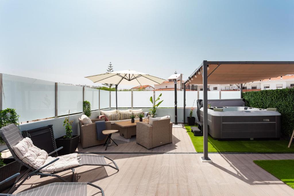 a patio with a hot tub and furniture on a roof at Linda s Guest House Alojamento 2 in Costa da Caparica