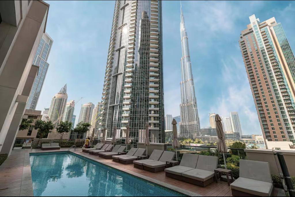 a swimming pool with chairs and a city skyline at Restay Homes at Act Towers - Pool access with Burj View in Dubai