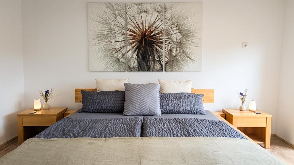 a bedroom with a bed with blue pillows and a painting on the wall at Ferienhaus Marcali - Erholung am Thermalbad und Plattensee in Marcali
