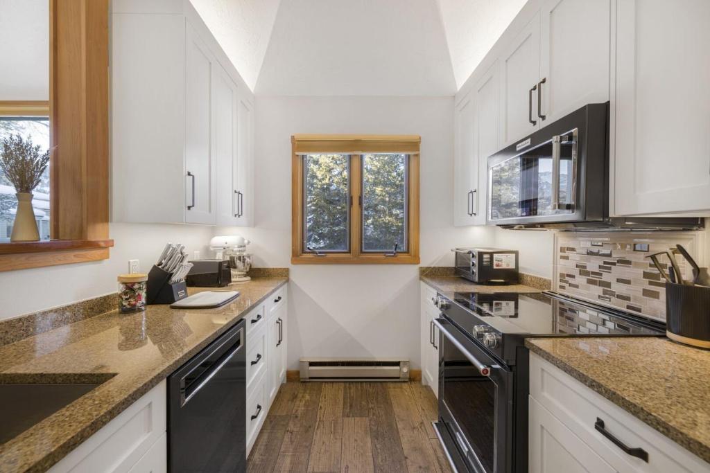 ウィルソンにあるRMR: Yarrow 2322 Condo in The AspensWilsonWYのキッチン(白いキャビネット、黒の電化製品付)