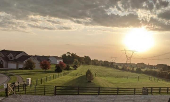 a field with a fence and the sun in the sky at The Calico Cottage in Lewis Center