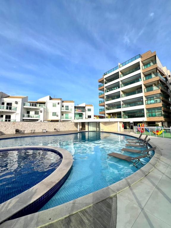 een groot zwembad met een gebouw op de achtergrond bij Paraiso dos Anjos in Arraial do Cabo