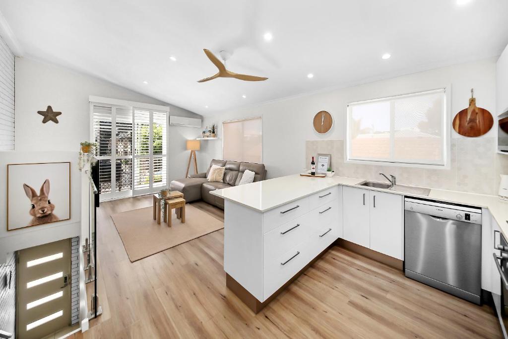 a kitchen with white cabinets and a living room at Popular Central Coastal Apartment in Maroochydore